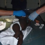 Infant on medical exam table with gloved hands