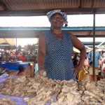 Woman selling ginger roots at outdoor market