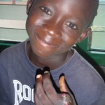 Child smiling and showing injured hand