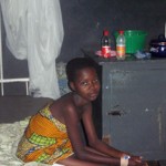 Child sitting on hospital bed beside metal cabinet