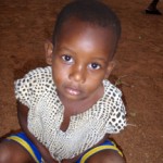 Child in crocheted top sitting on dirt